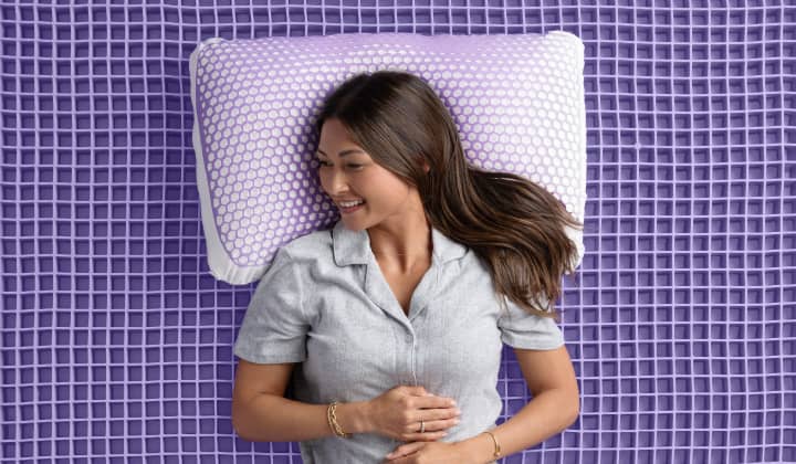 young woman lying on her back on a bare purple mattress