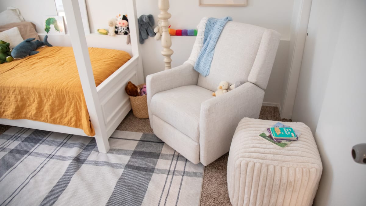 A white swivel glider recliner in a modern child's room