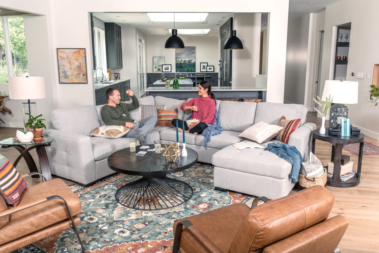 Light gray fabric sectional in open concept Living Room featuring couple with popcorn