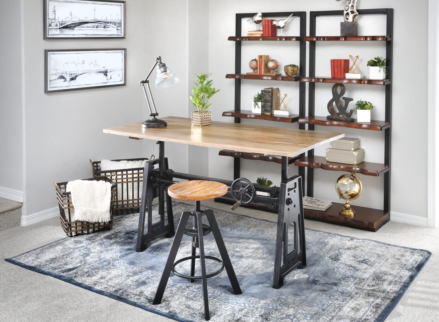 The Crank Adjustable Table poased in a gray room accompanied by book shelves
