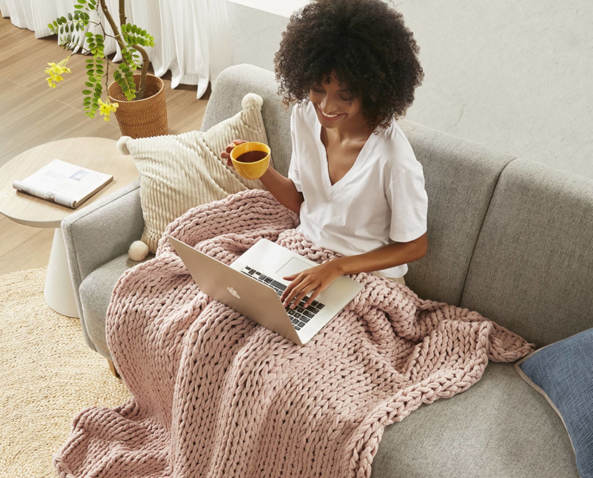 Woman posed on couch with the Chunky Double Knit Handmade Blush Throw Blanket