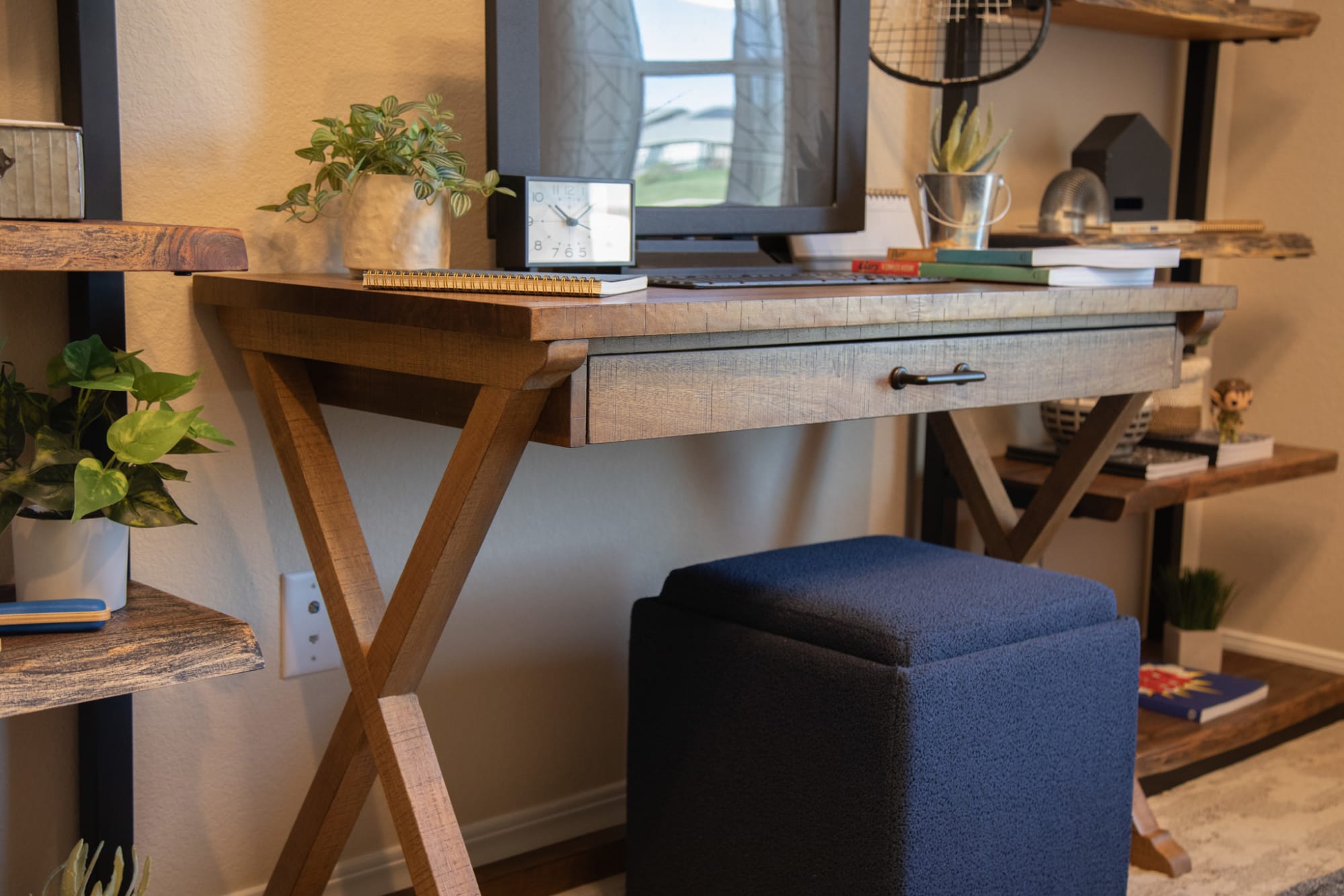 The Boston Writing Desk accompanied by a Fenn Ottoman w/ Tray in navy upholstery posed against a wall