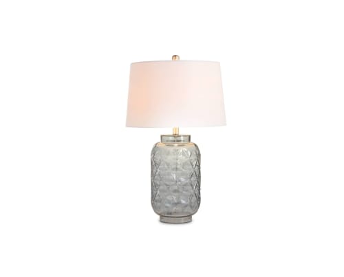 A glass table lamp with beige shade