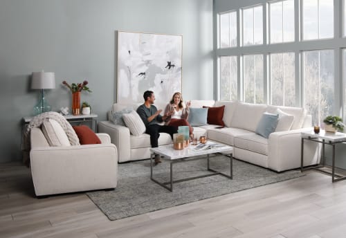 Couple sitting on cream colored sectional dancing in living room