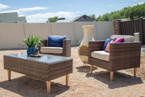Wicker chair set with wicker glass top coffee table in yard with fire pit.