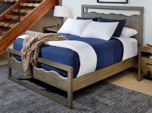 A wood framed queen bed with curvy cut-outs along the headboard and footboard, placed in a contemporary bedroom