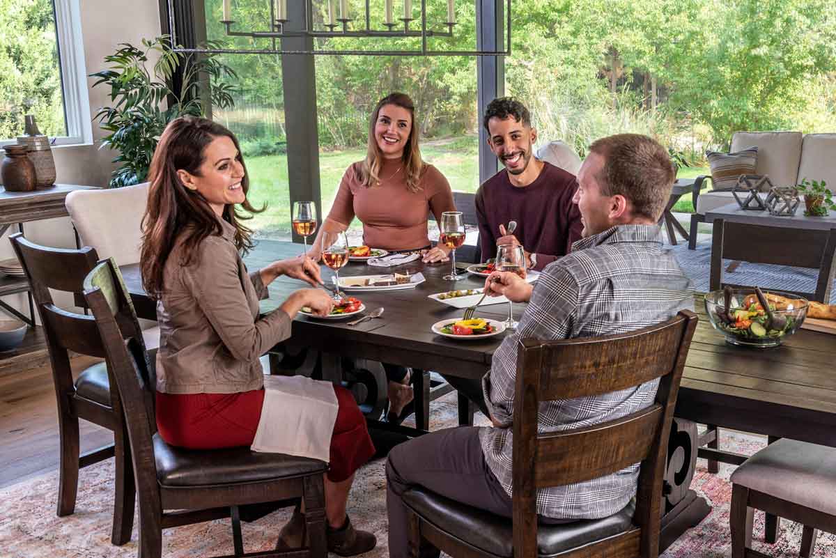 four friends sitting and eating together around the Sedona Dining Table