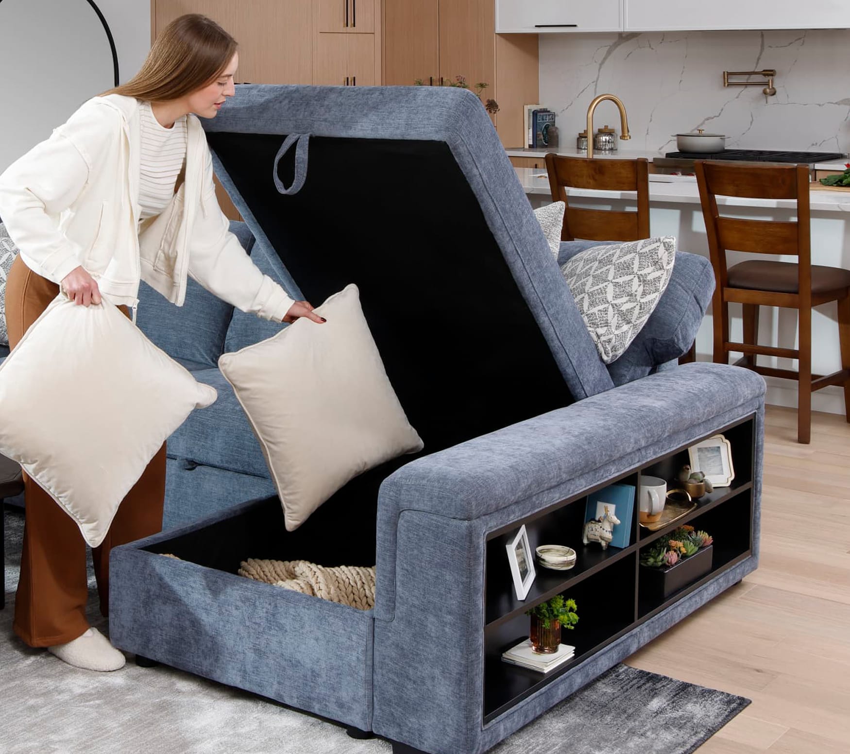 Woman putting pillow in Blue microvelvet sectional with storage chaise
