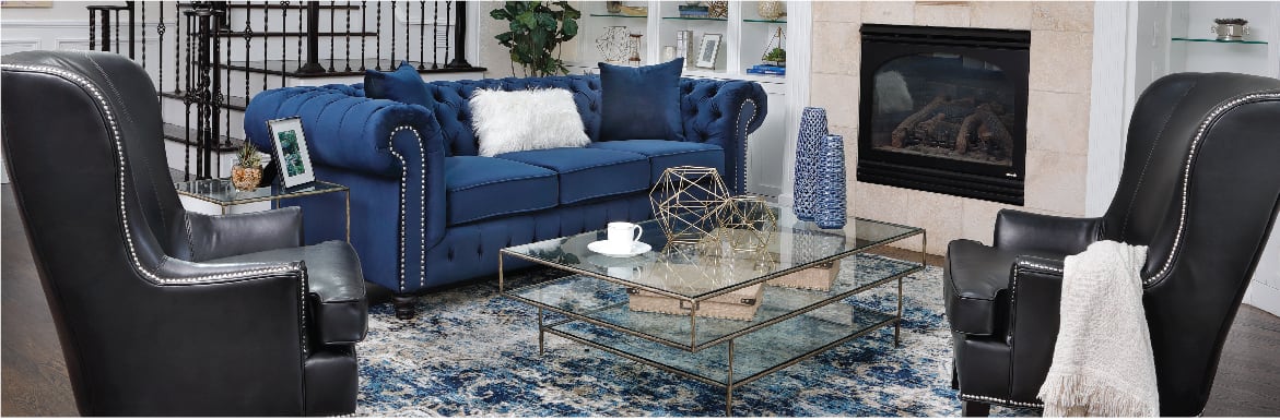 Traditional royal blue sofa with nail head trim accompanied by black wingback chairs with nail head trim