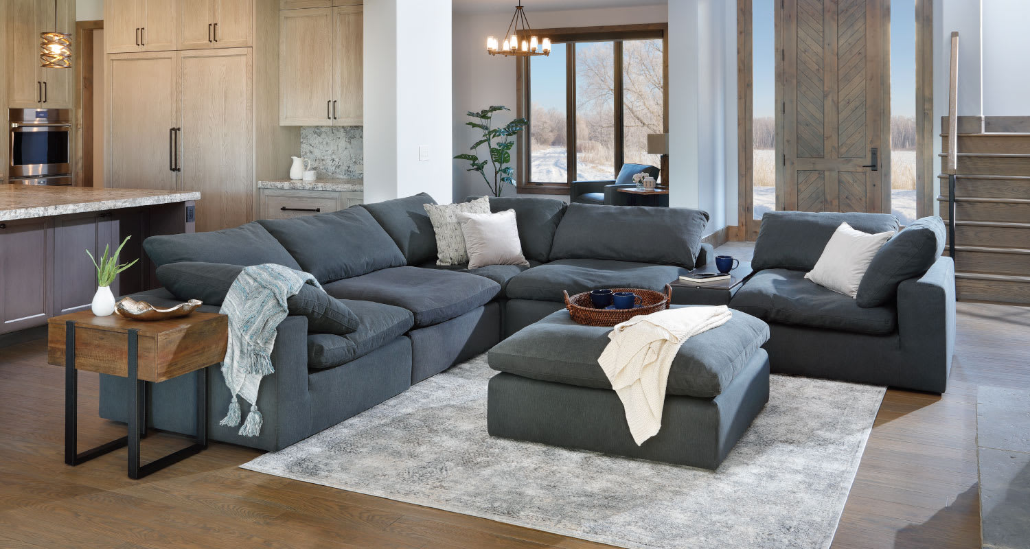 The deep gray Luscious Sectional styled in an open living room with matching Luscious Ottoman