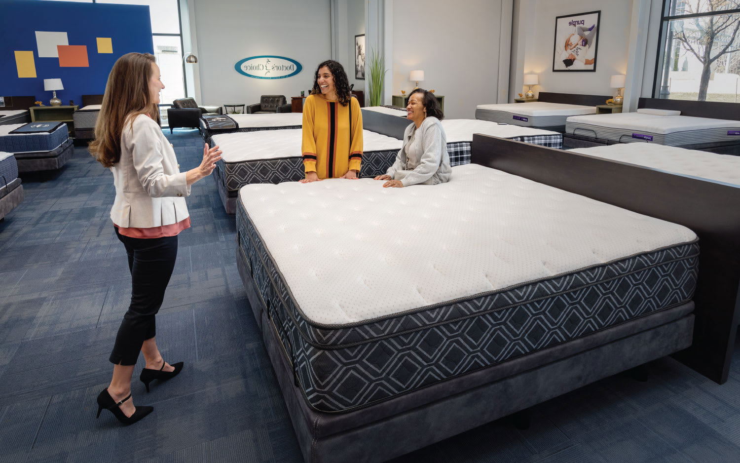 Sales Person with Customers Sitting on Mattress at Denver Mattress Store