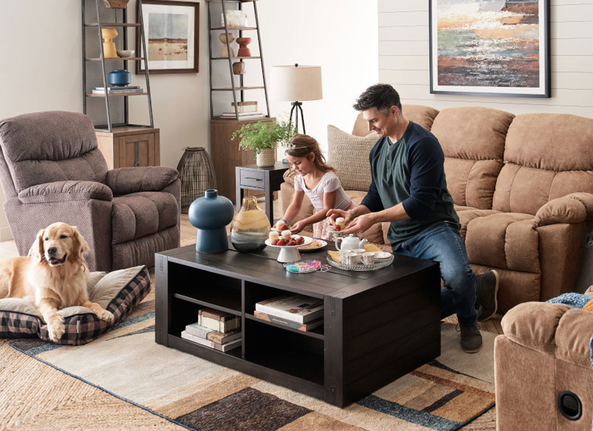 Man and his daughter having a tea part at the coffee table surrounded by morrison lazboy sofa set and golden retriever