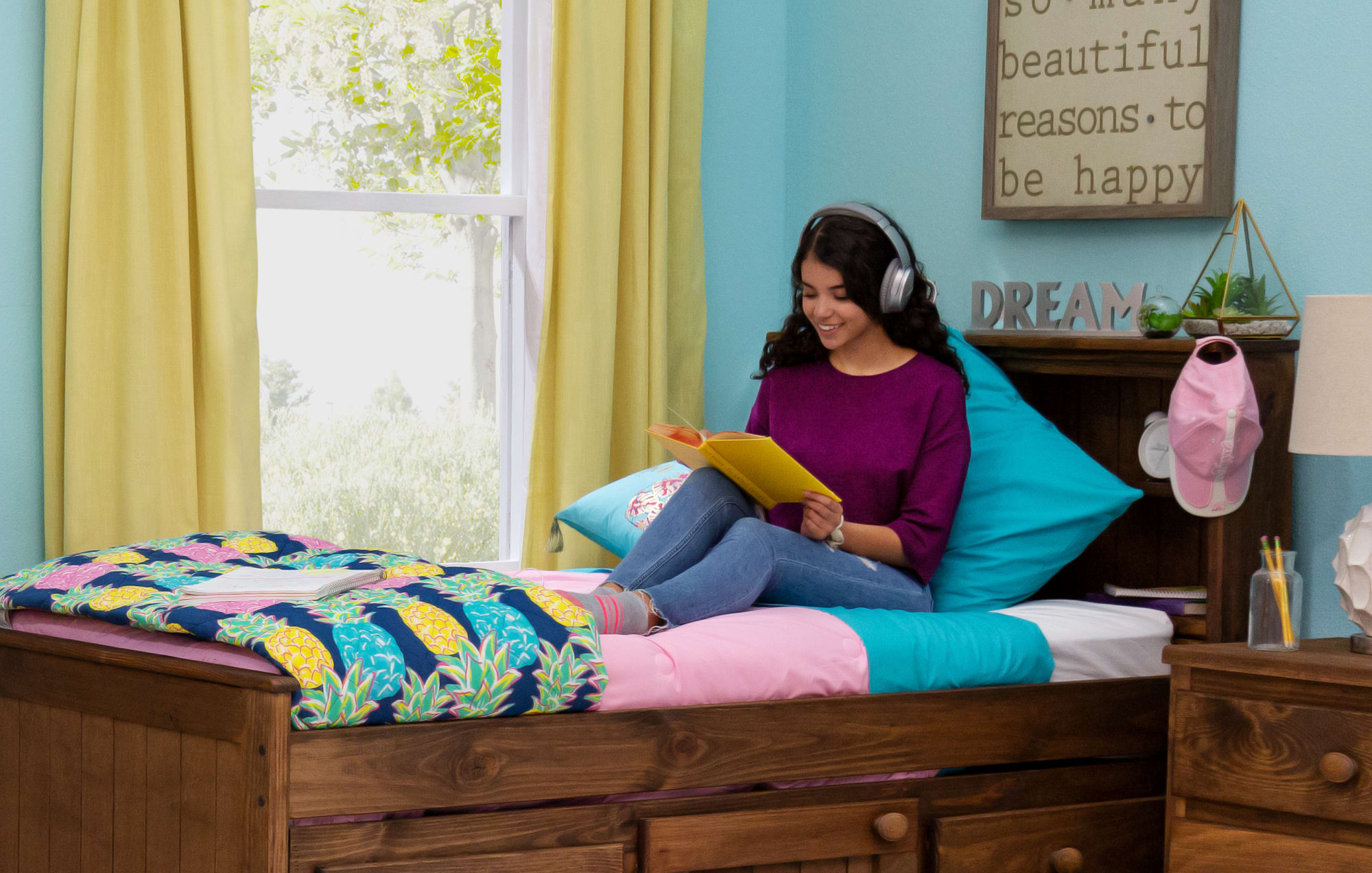 student sitting on bed with headphones and notebook