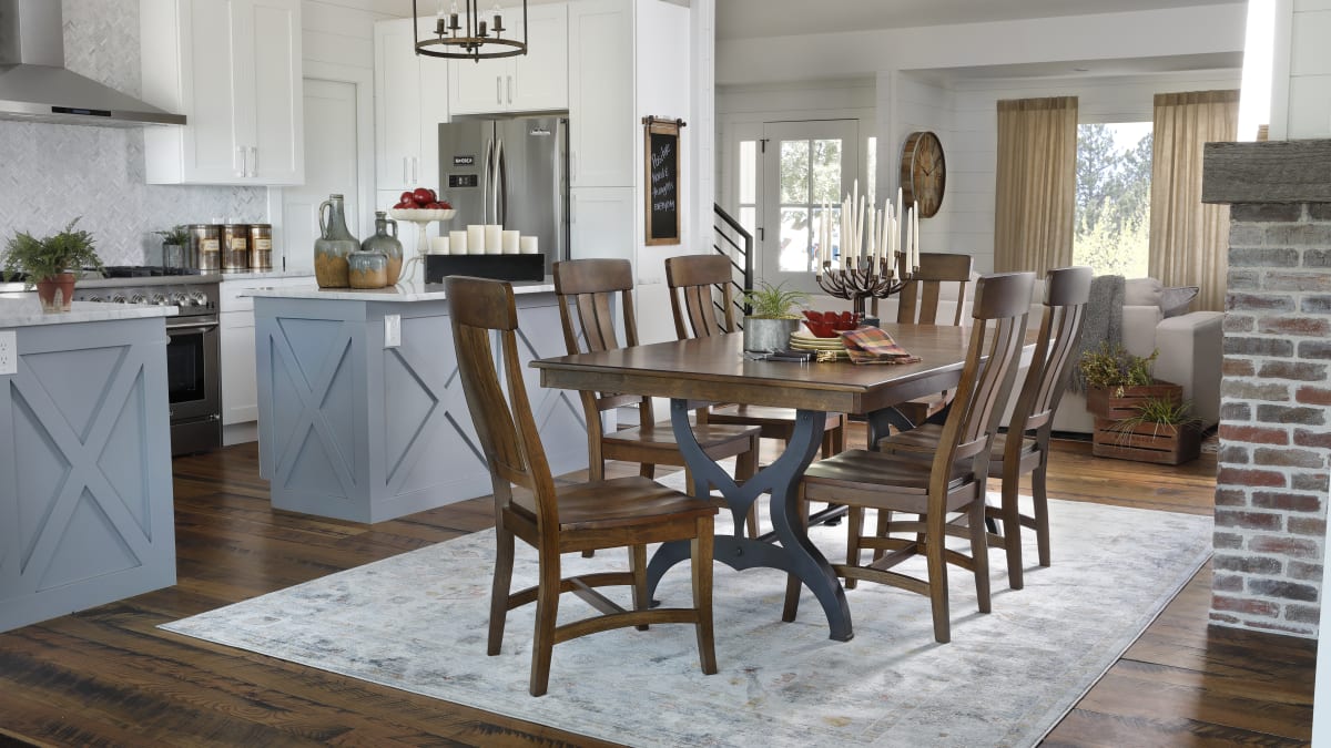 A rustic-contemporary dining set featuring a rectangular table with a metal base and four wood dining chairs in a dining room