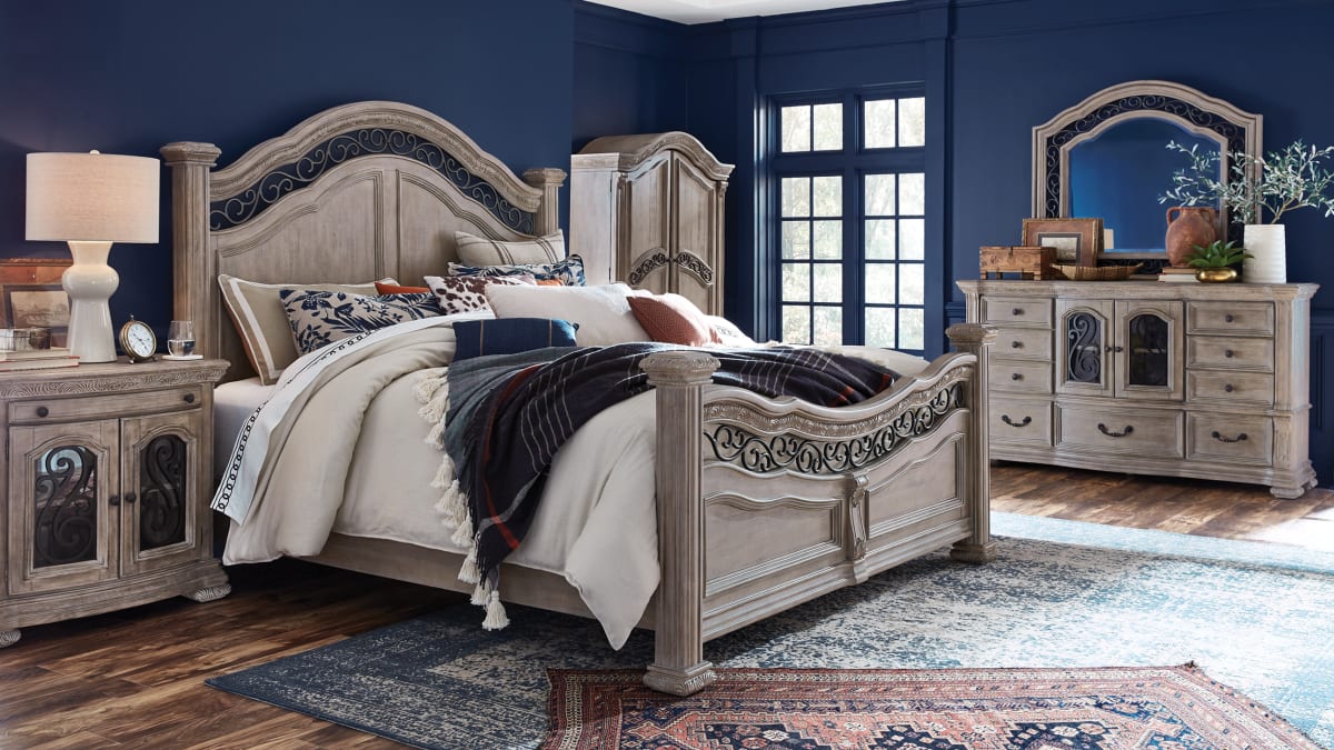 A large, richly decorated wooden bed with matching bedroom pieces in a bedroom