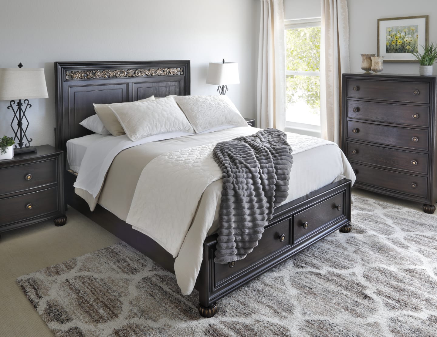Deep brown traditional style bed with footboard storage accompanied by nightstands and dresser in bedroom window scene