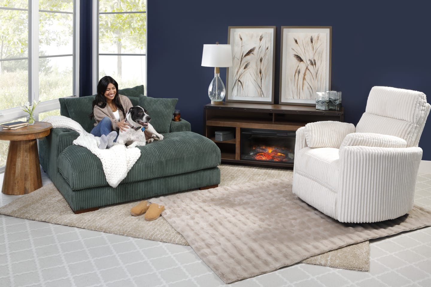 Person and dog on green oversized chaise with ivory accent chair in a window scene