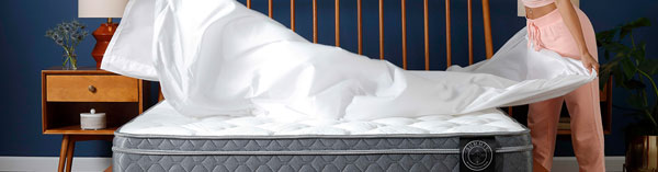 young woman spreading sheets on a new mattress