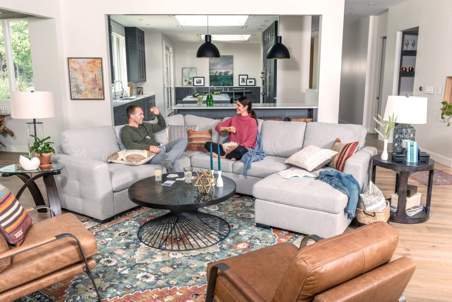 Light gray fabric sectional in open concept Living Room featuring couple with popcorn