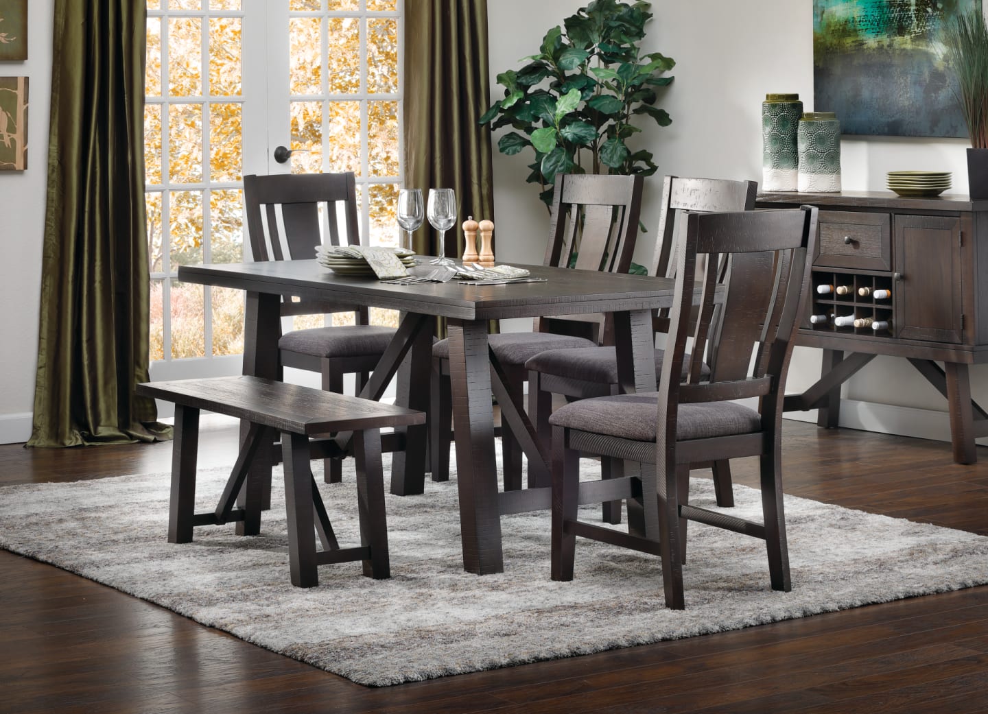 Classic farmhouse dark wood dining set with bench and four chairs accompanied by matching server in dining room window scene