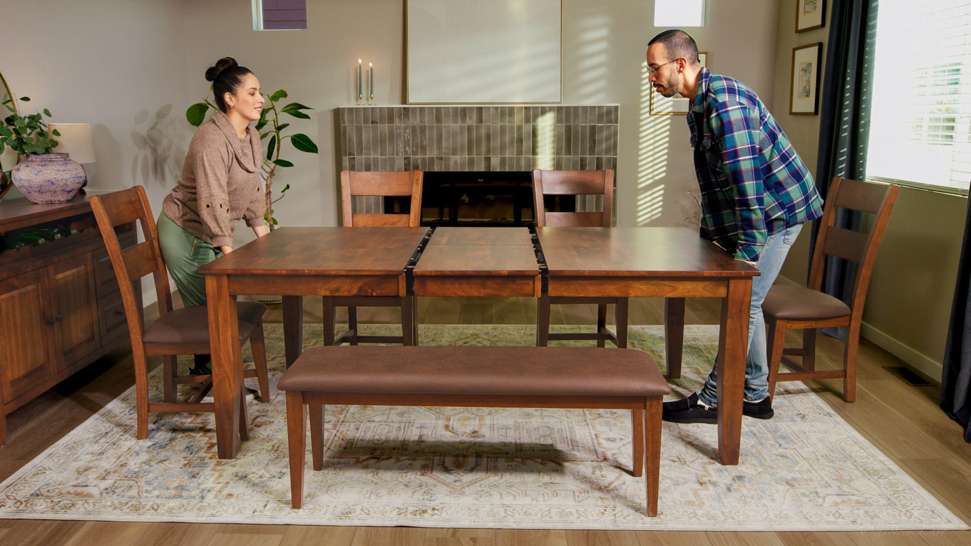 Largo Extendable Wooden Dining Table in Warm Finish. Couple taking out table leaf.
