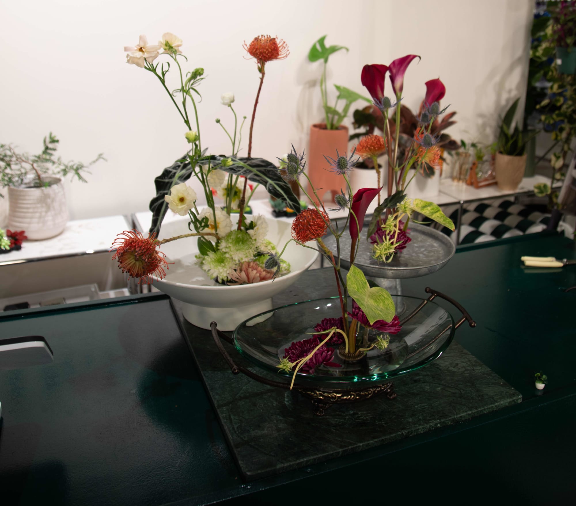 Three ikebana flower arrangements on counter