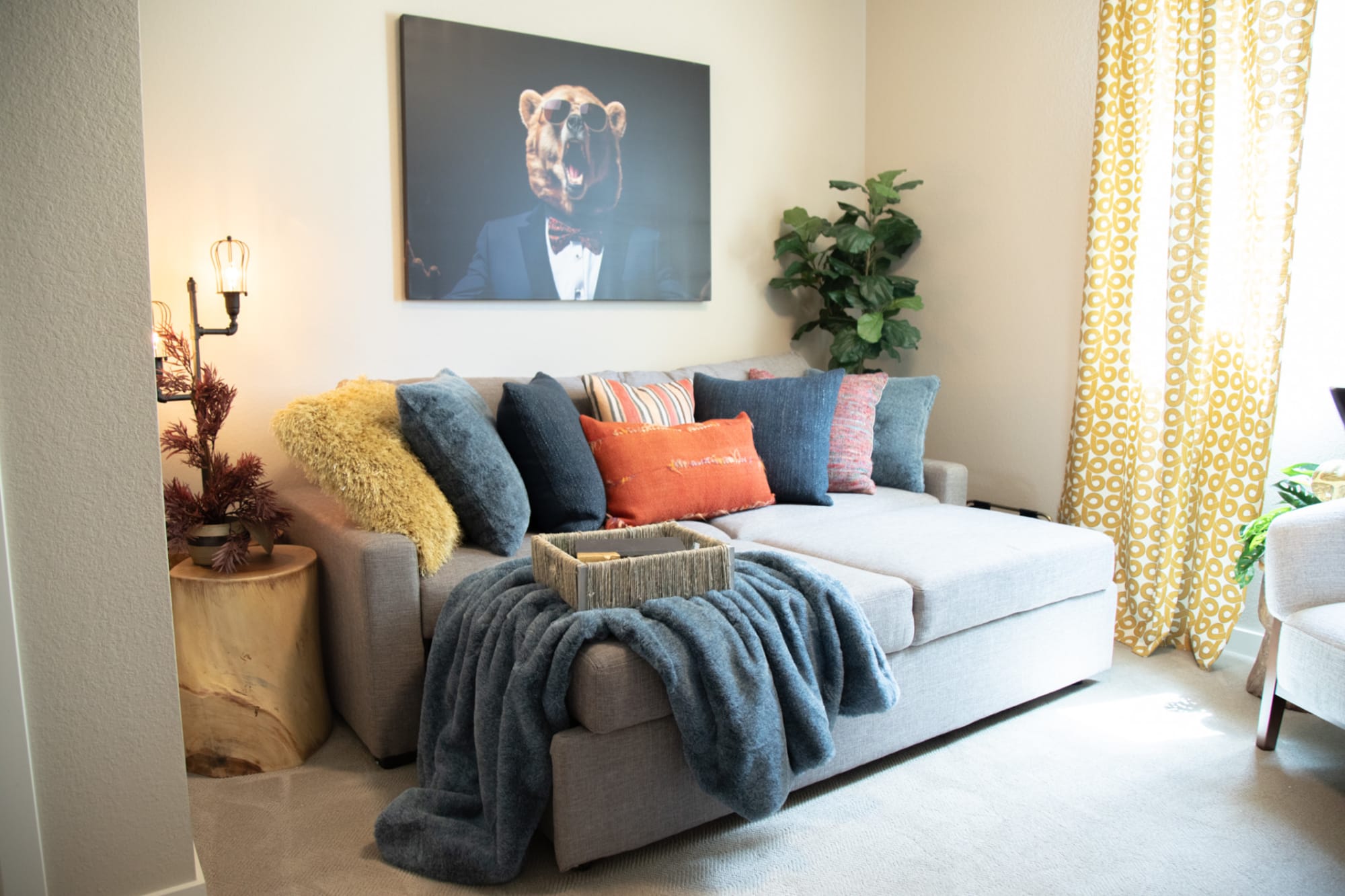 A small sofa with an extended sleeping chaise topped with pillows with comfy fabrics