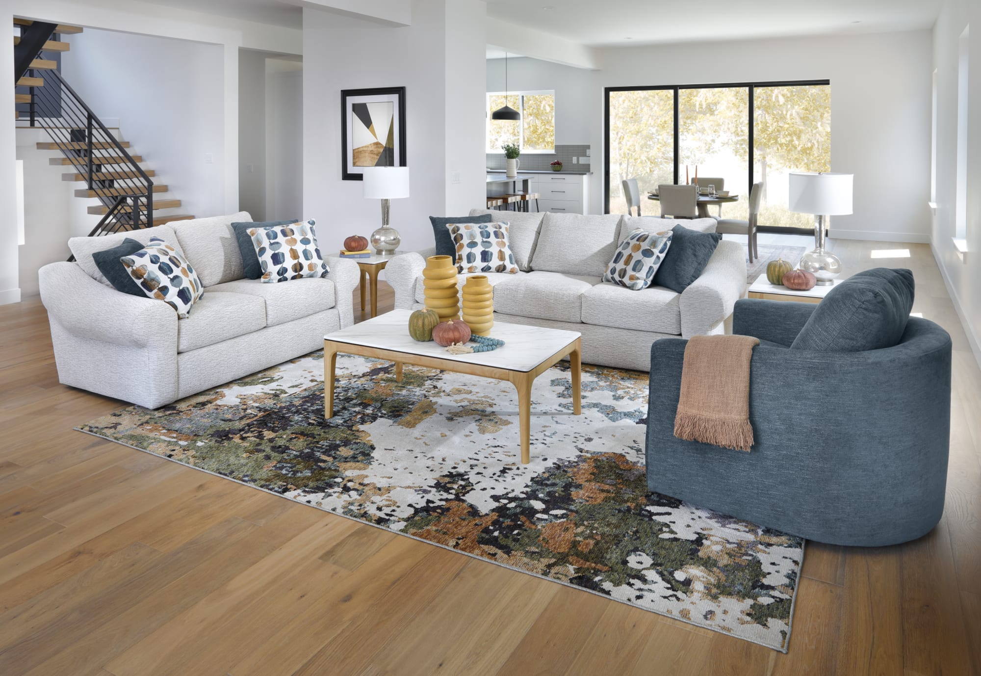 A white sofa and loveseat with large round arms, along with a round blue accent chair, in an uplifting contemporary space