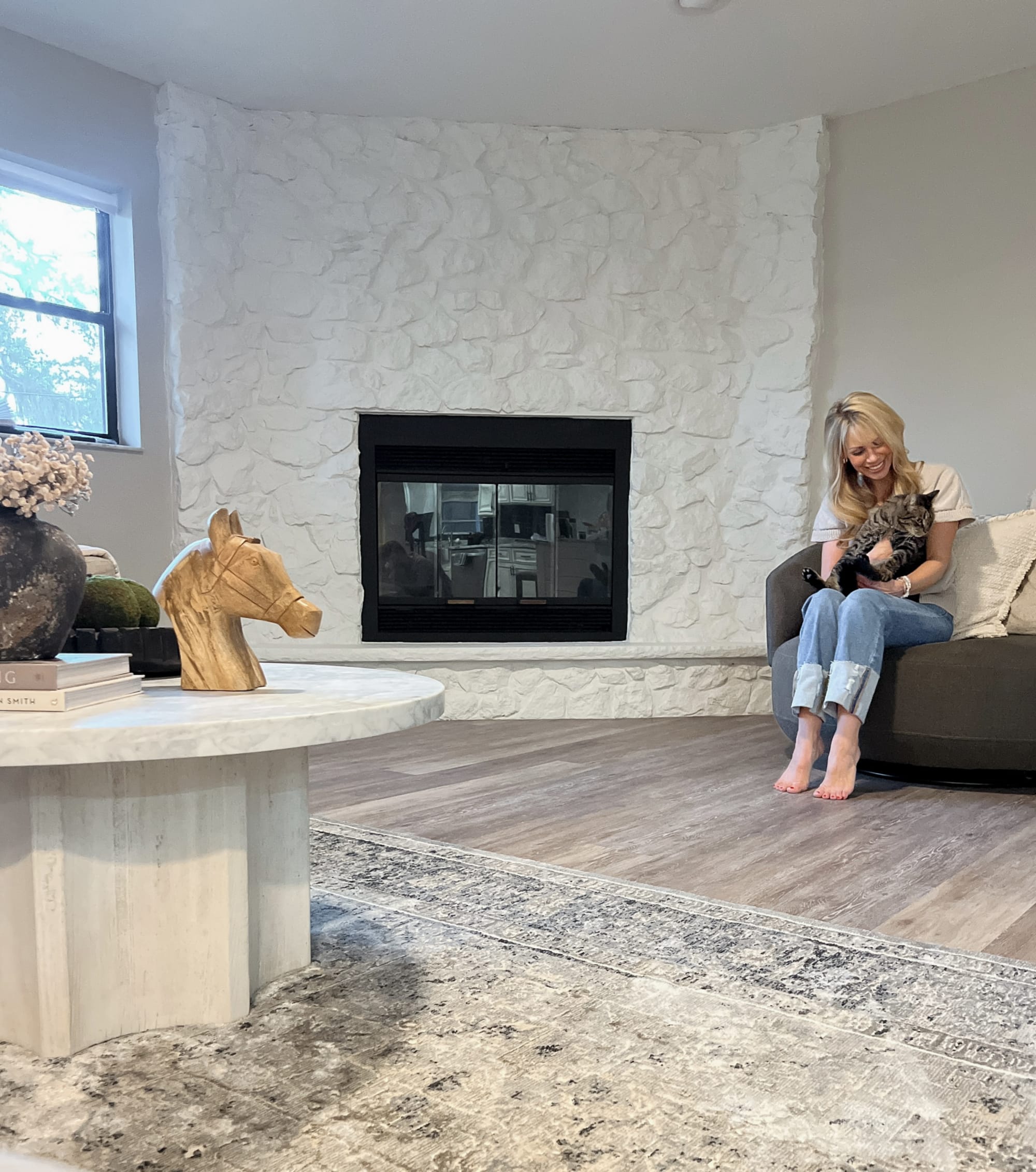 Kelli Bateman in her AirBnB Family Room holding a cat in front of a fireplace