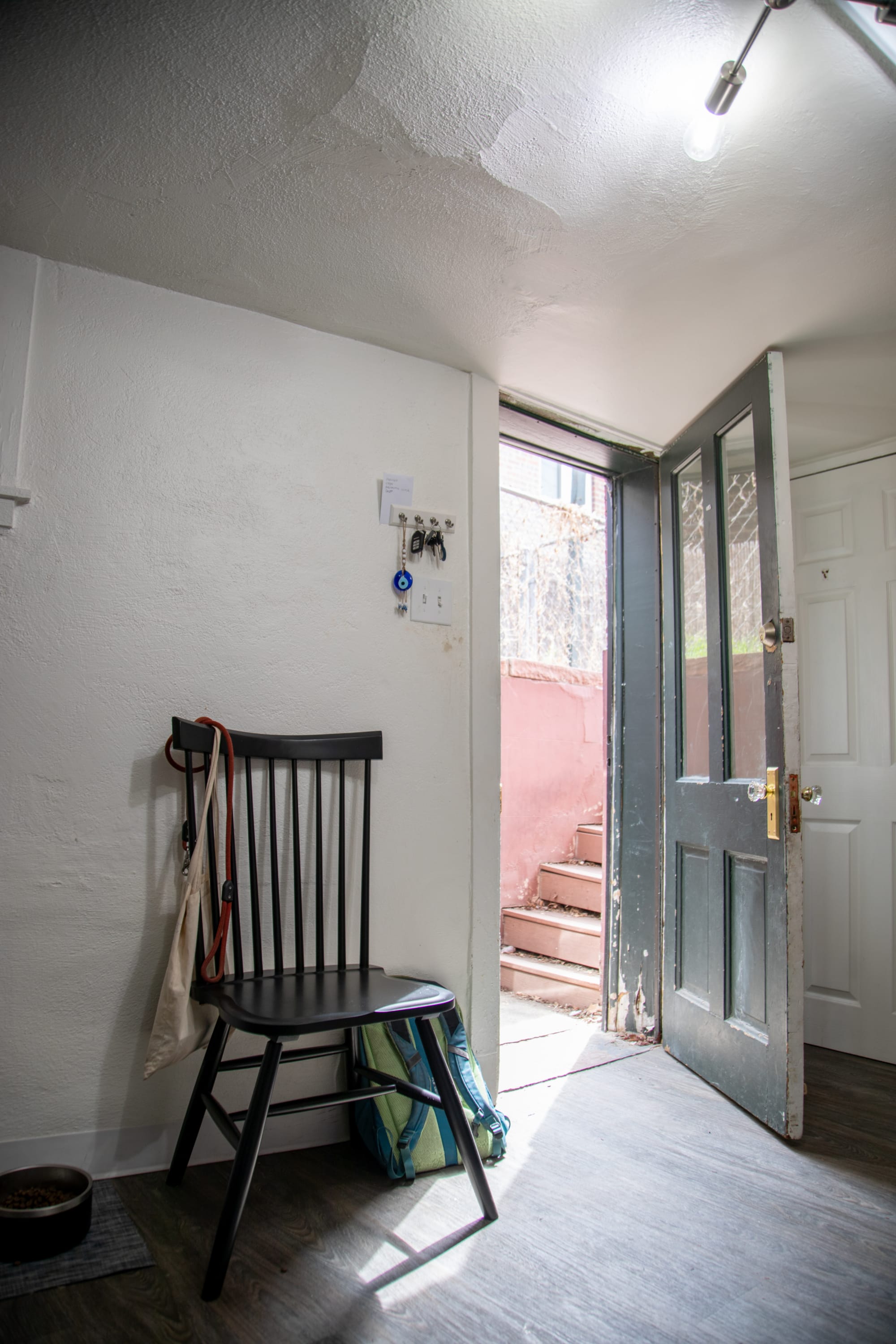 The La Paz Dining Chair styled by Mackinley's apartment front door, which can also double as shoe storage or extra seating