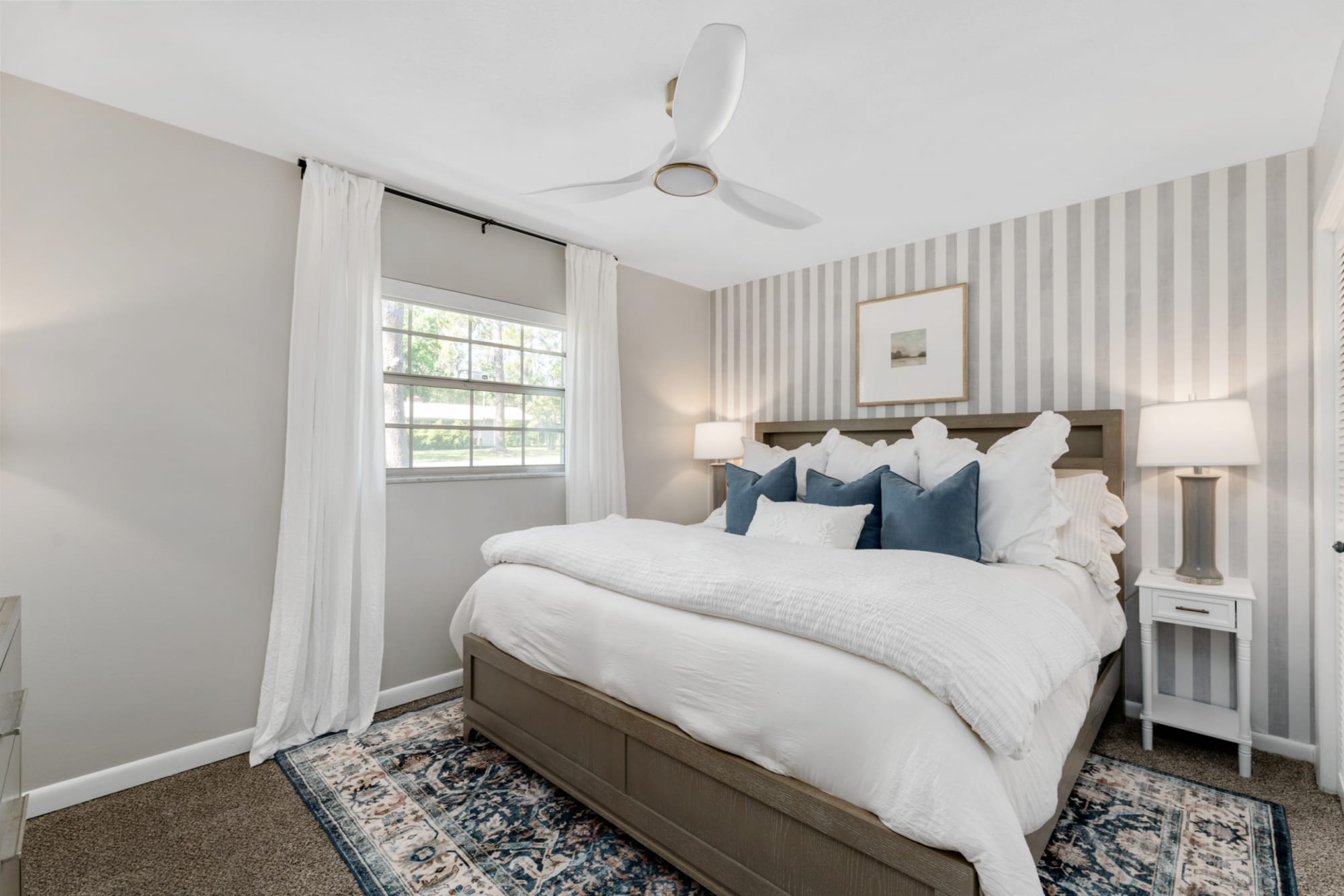 Large wood framed panel bed with upholstered headboard and white sheets in in Kelli Bateman's Home