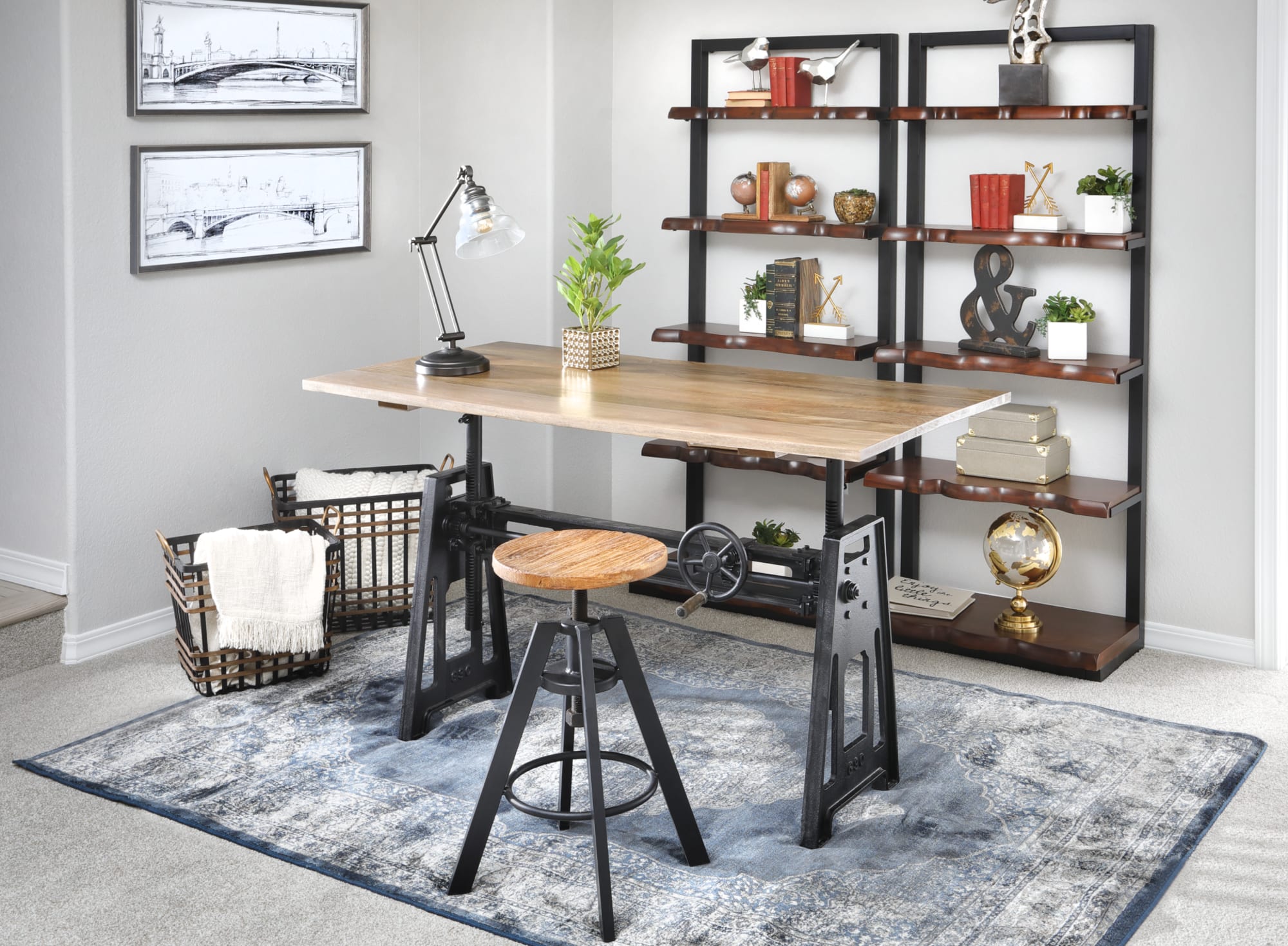 The Crank Adjustable Table poased in a gray room accompanied by book shelves