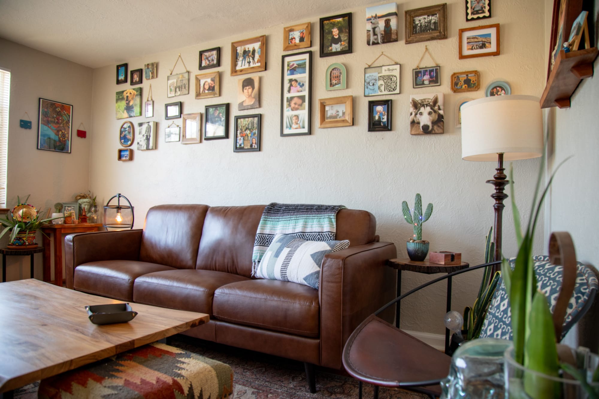 A brown leather sofa styled in home beneath a gallery photo wall
