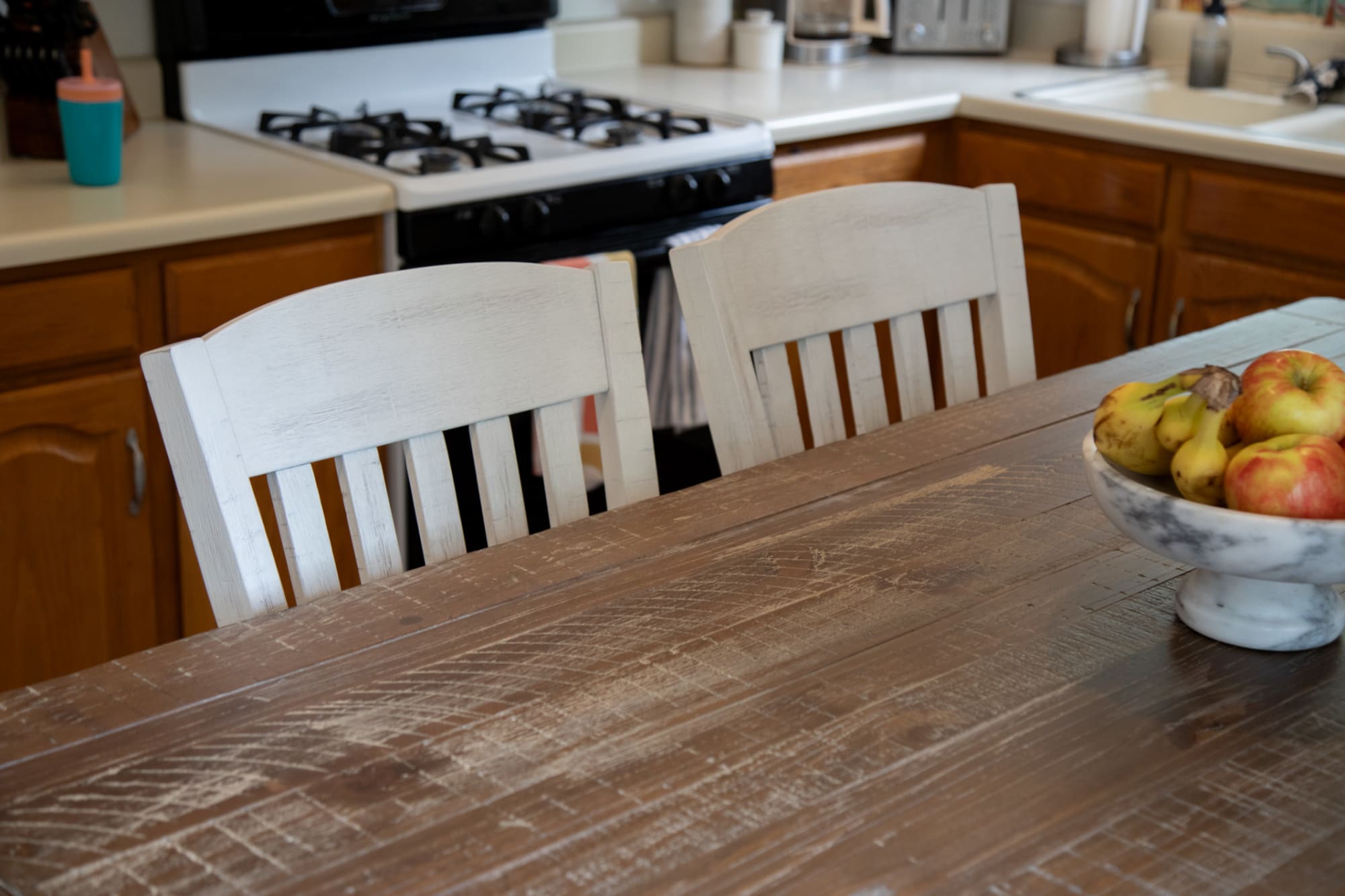 A distressed table top and two wood bar stools in a kitchen space