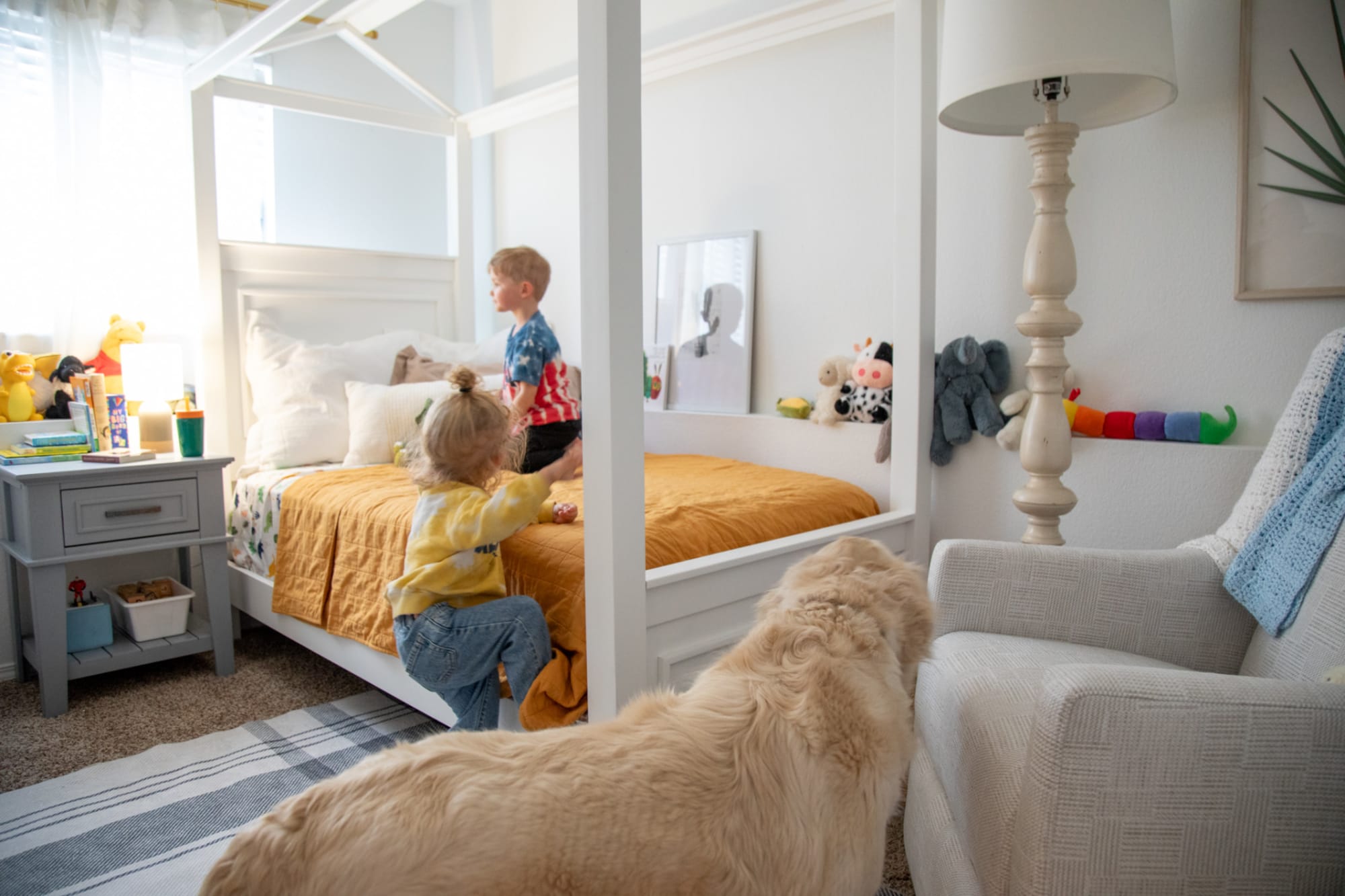 Kids playing on a white canopy bed in a contemporary bedroom