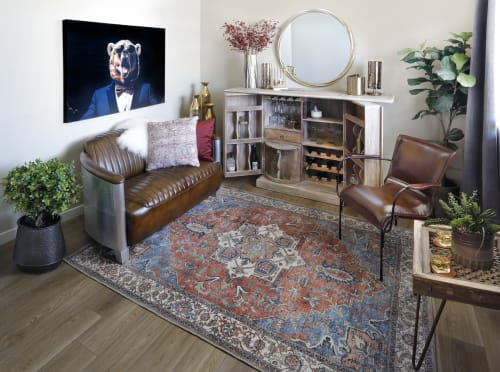 A modern loveseat with leather seats and a metallic back along with a leather accent chair in an eclectic room with bold colors