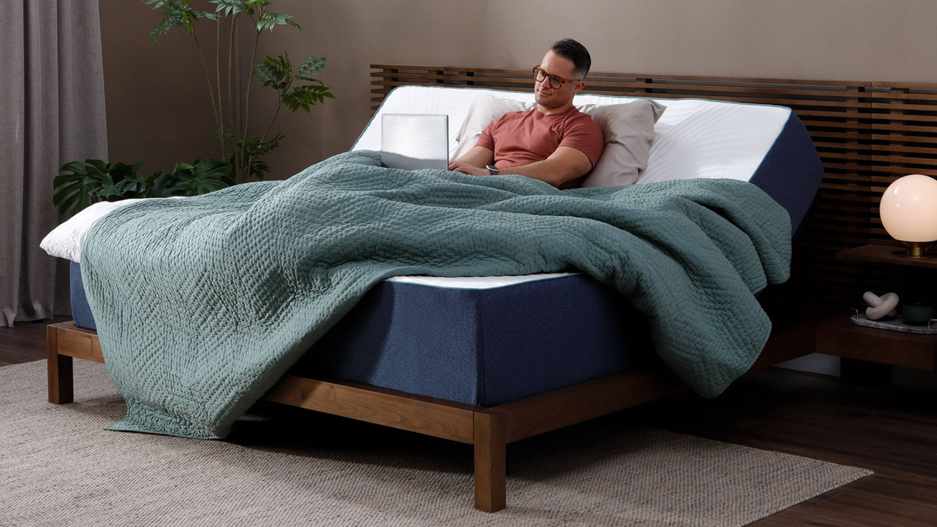 Man sitting on adjustable bed working on laptop