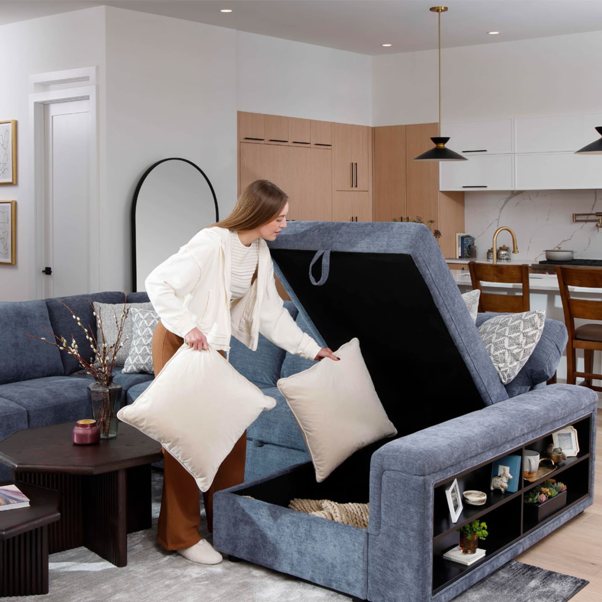 Woman putting pillows in Blue Fabric Storage Sectional