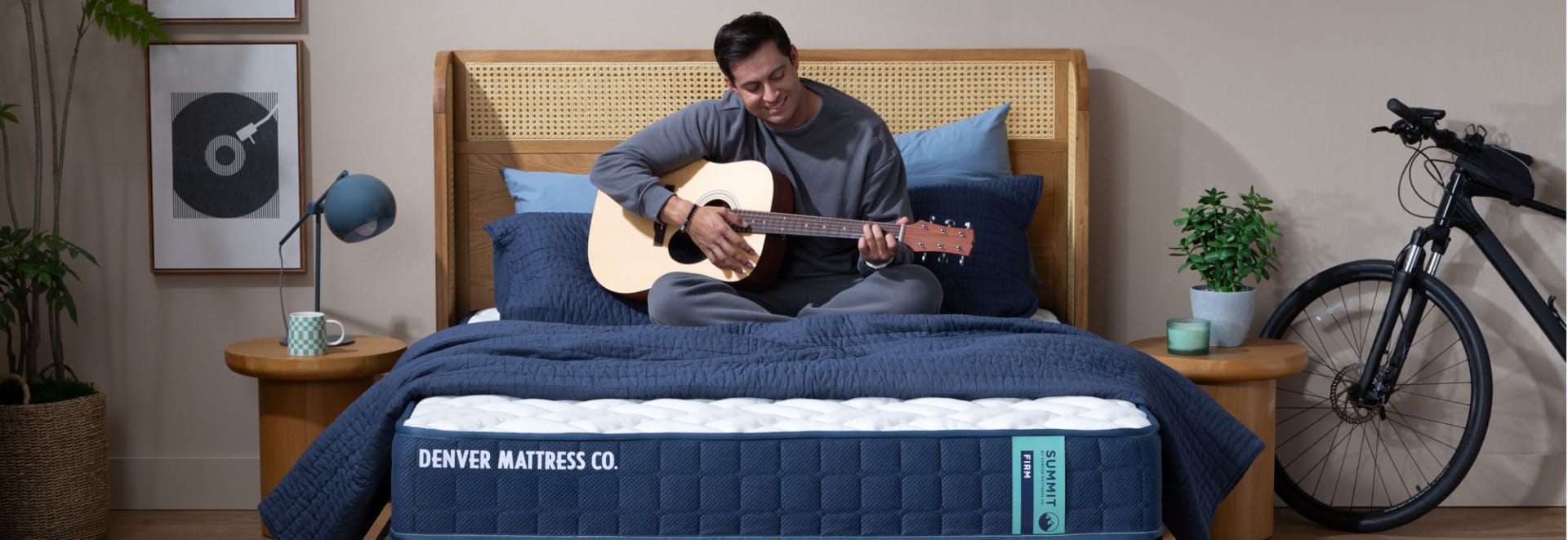 Man Sitting on Summit Mattress in Bedroom Playing Guitar