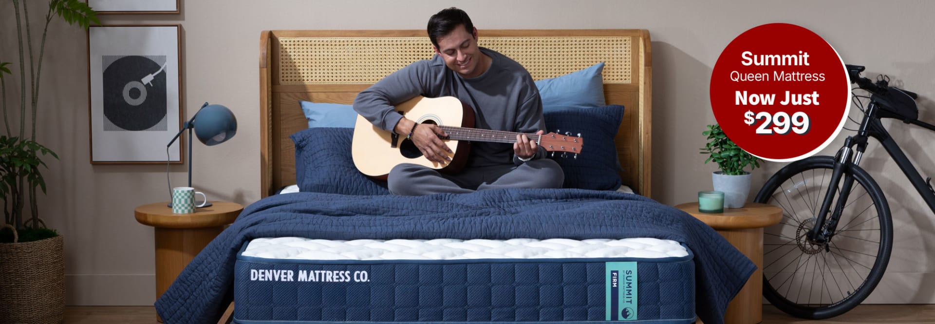 Man Sitting on Summit mattress in bedroom with guitar. Summit Queen Mattress. Now Just $299.