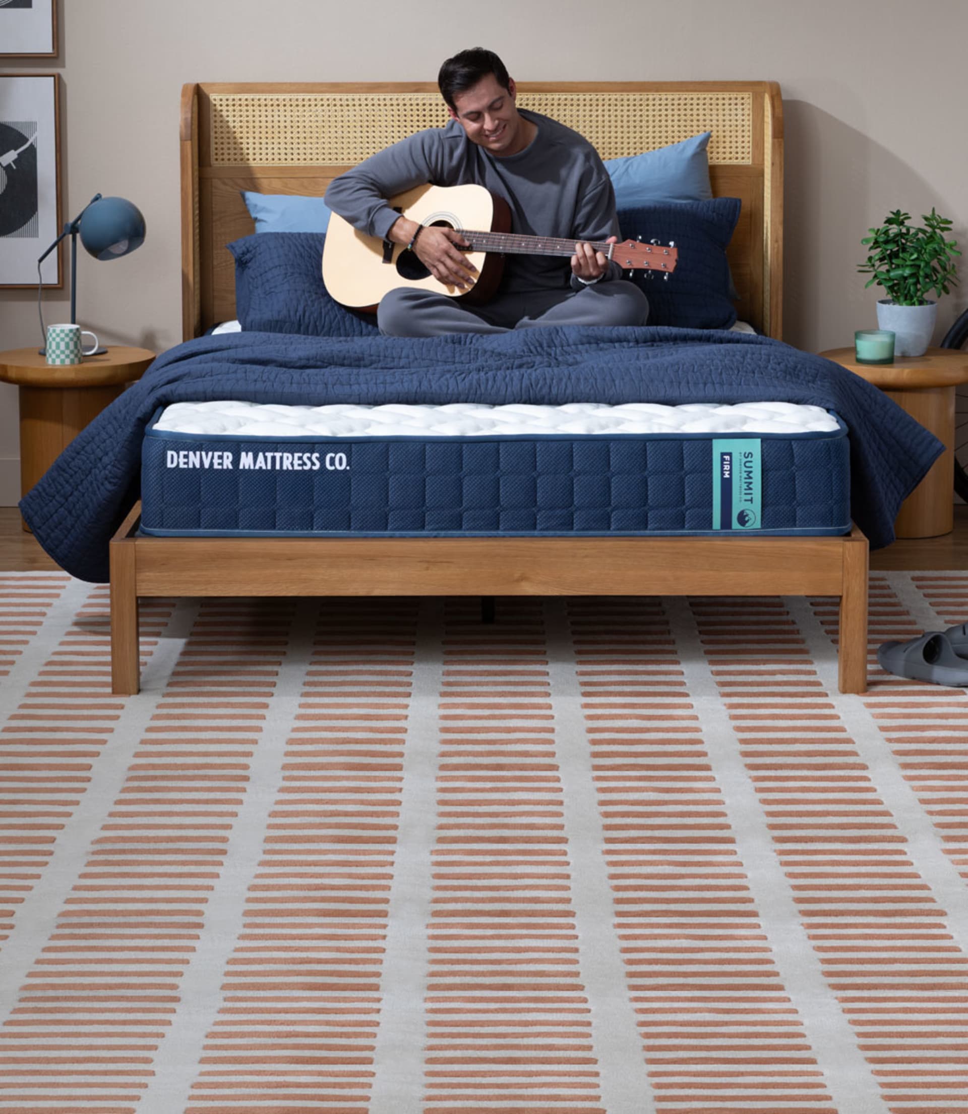 Man Sitting on Summit Mattress in Bedroom Playing Guitar
