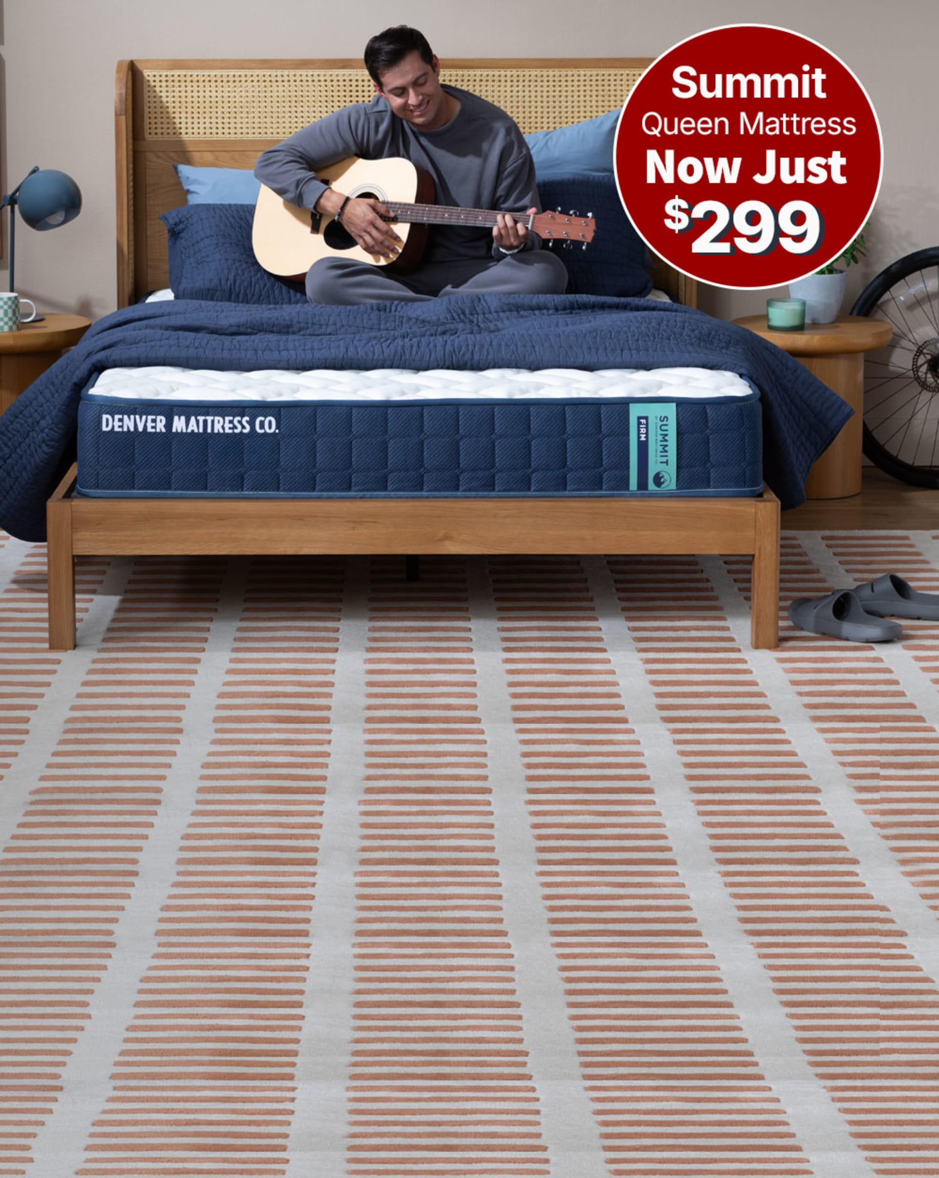 Man Sitting on Summit mattress in bedroom with guitar. Summit Queen Mattress. Now Just $299.