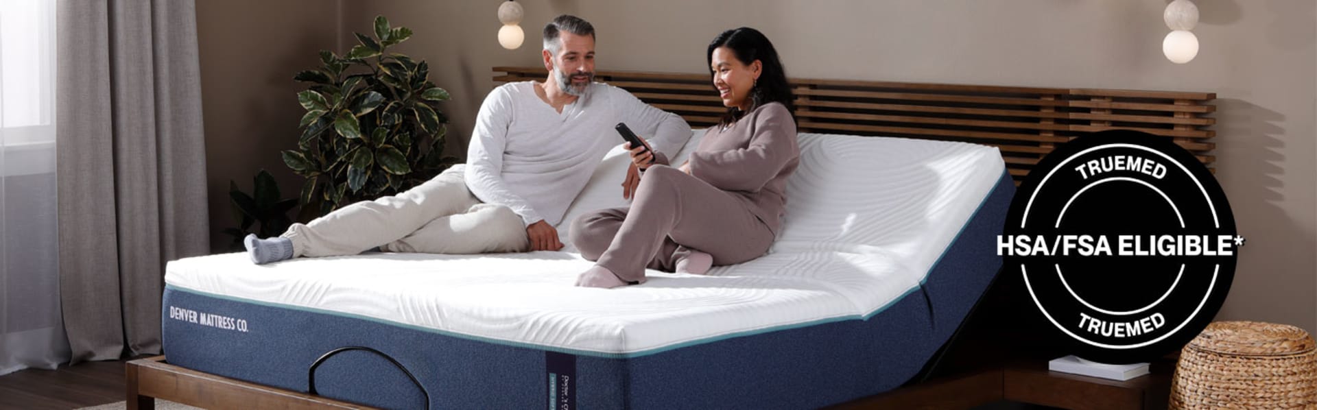 Couple sitting on Doctors Choice Hybrid on Adjustable Mattress. TrueMed HSA/FSA Eligible.