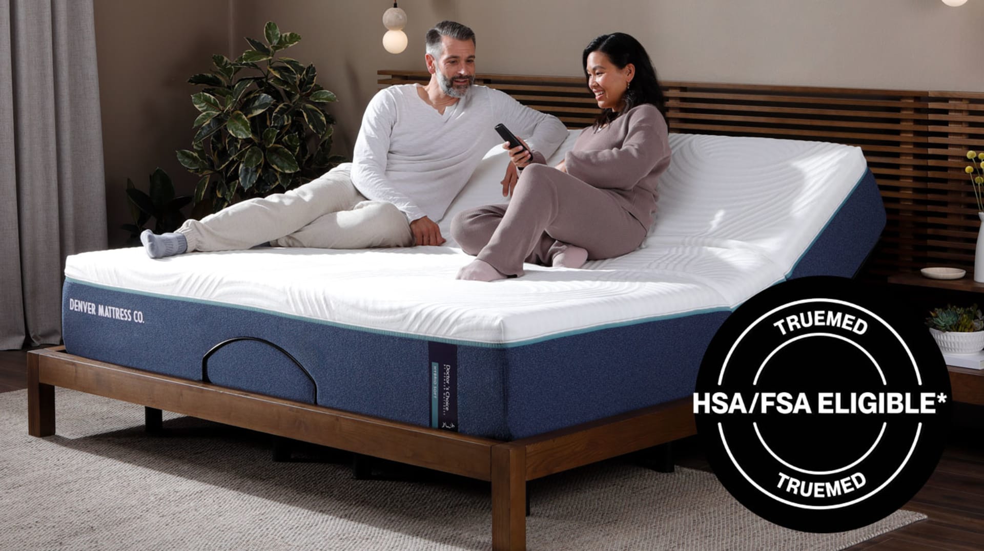 Couple sitting on Doctors Choice Hybrid on Adjustable Mattress. TrueMed HSA/FSA Eligible.