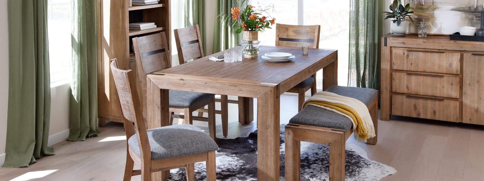 Light wooden dining table with metal accents and grey undertones in dining room.