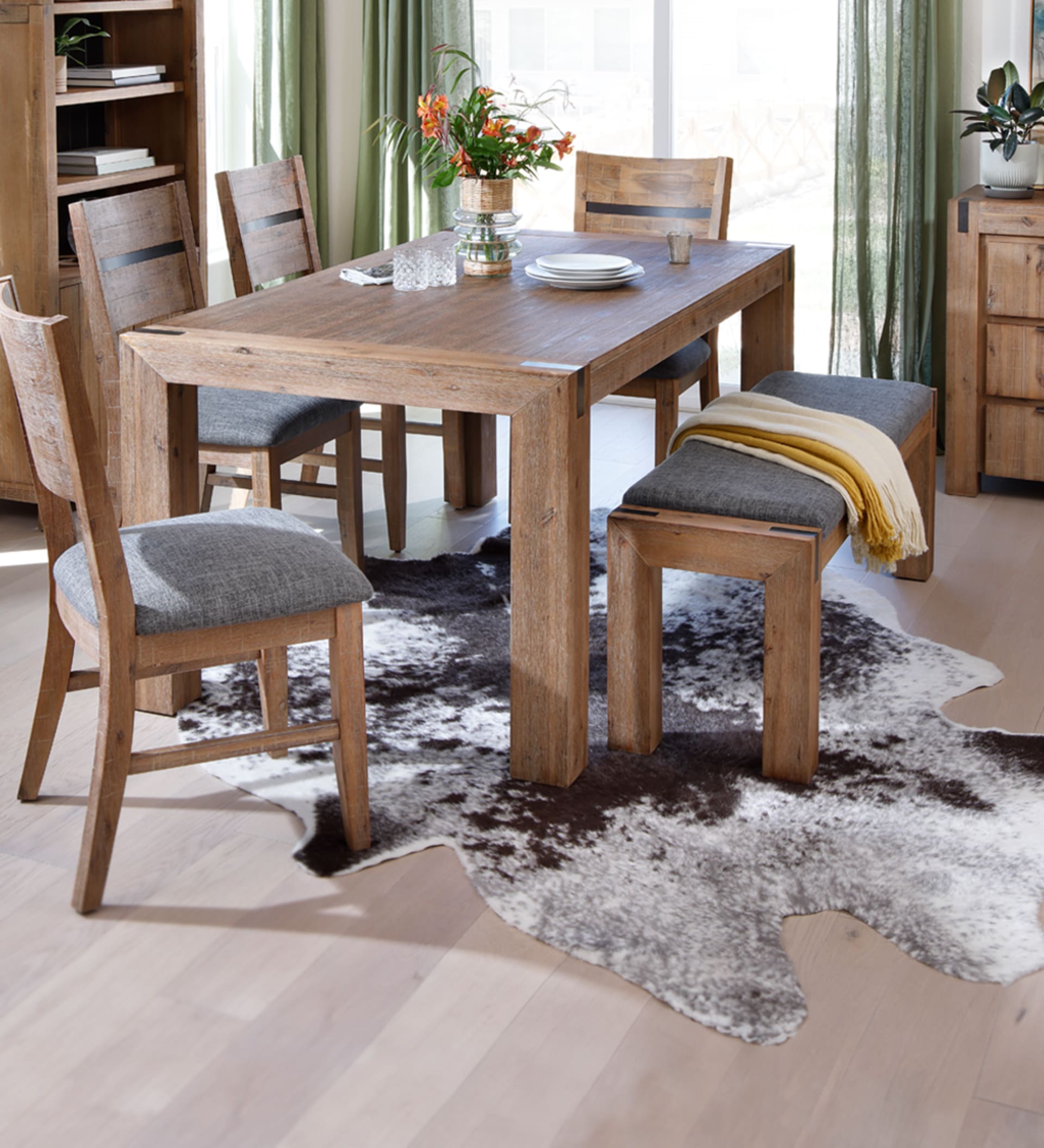 Light wooden dining table with metal accents and grey undertones in dining room.