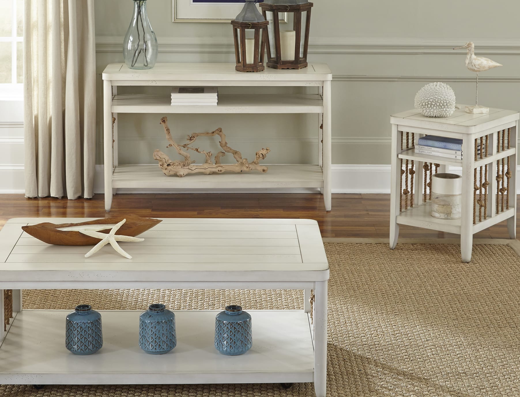 A white wood coffee table, end table, and sofa table set with rope accents and coastal decor