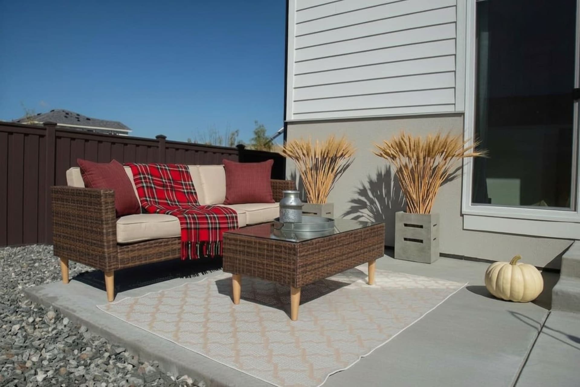 The San Bruno Patio Set staged on an open front porch with red-toned fall decor