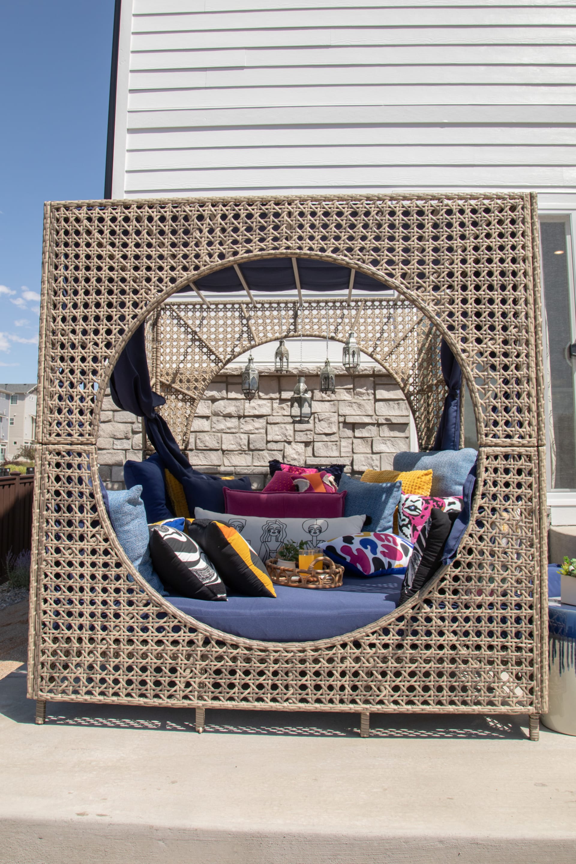 The Moonstone Cove Wicker Daybed styled on a back patio with cushions and accent pillows