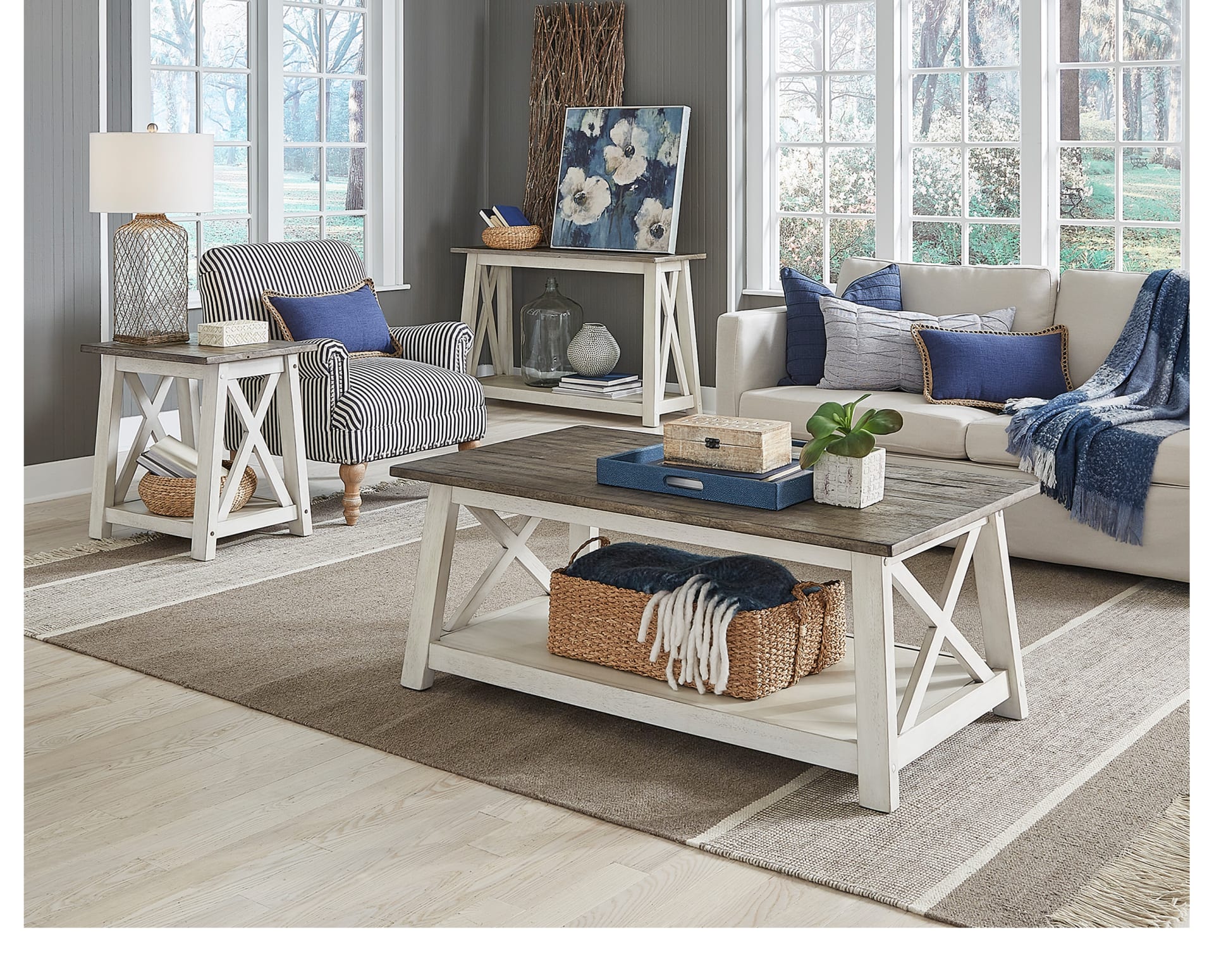 A rectangular coffee table with a white base and brown planked top in a coastal living room